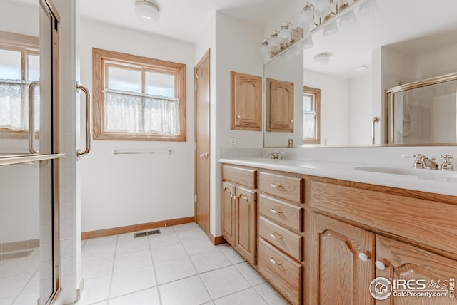 full bathroom with a sink, tile patterned floors, a stall shower, double vanity, and baseboards