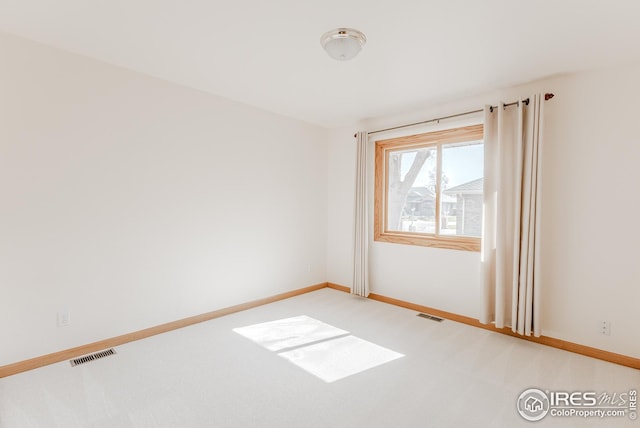 empty room with visible vents, light colored carpet, and baseboards