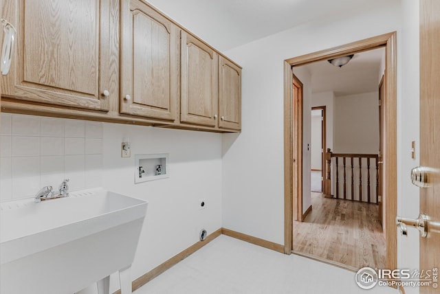 clothes washing area with cabinet space, hookup for an electric dryer, washer hookup, a sink, and baseboards