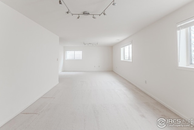 unfurnished room featuring rail lighting, baseboards, and carpet floors