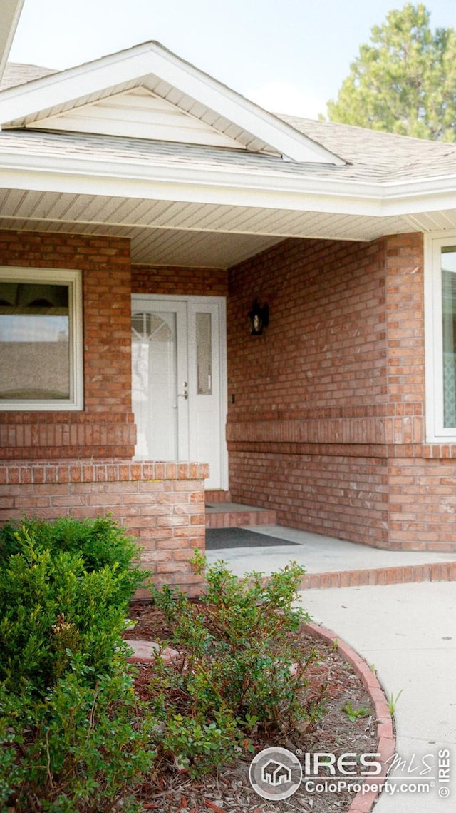 entrance to property with covered porch and brick siding