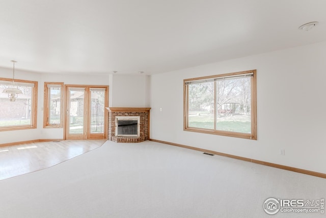 unfurnished living room with baseboards, visible vents, carpet, and a brick fireplace