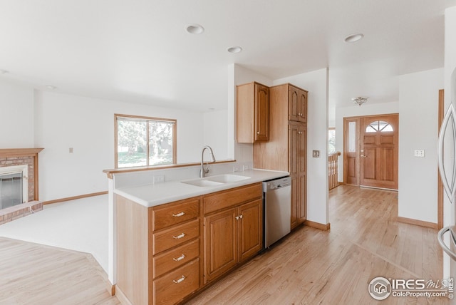 kitchen with stainless steel dishwasher, a sink, light countertops, plenty of natural light, and light wood-type flooring