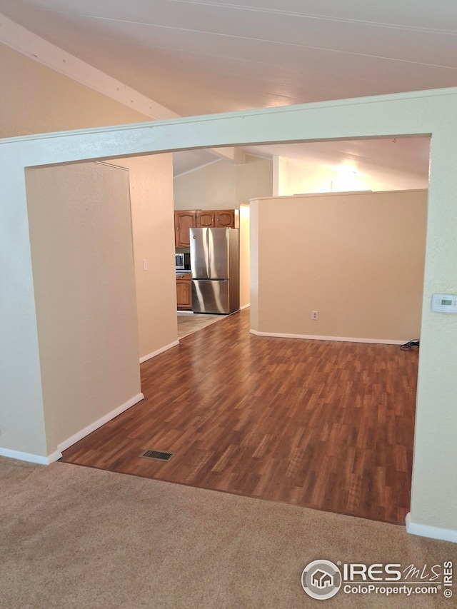 spare room featuring baseboards, visible vents, vaulted ceiling with beams, and dark wood finished floors