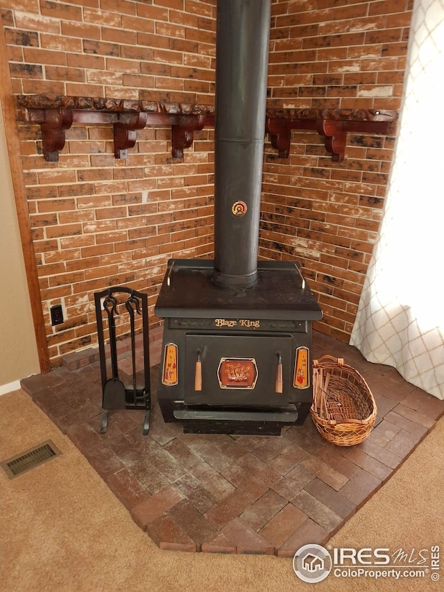 room details featuring visible vents, a wood stove, and carpet