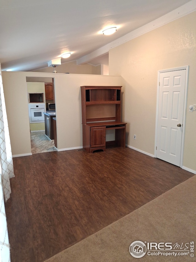 unfurnished living room with vaulted ceiling with beams, wood finished floors, and baseboards
