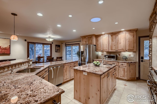 kitchen with a sink, a center island with sink, light brown cabinetry, and stainless steel appliances