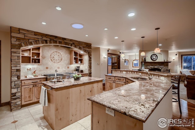 kitchen with a large island with sink, open shelves, a sink, and light brown cabinetry