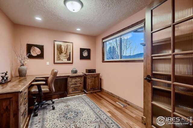 office featuring a textured ceiling, recessed lighting, wood finished floors, and visible vents