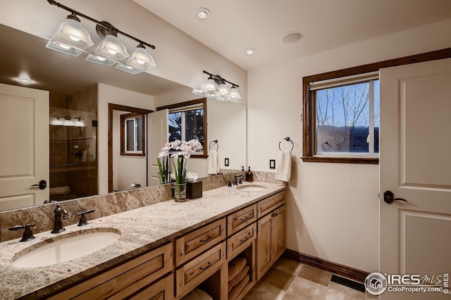 full bath featuring a sink, baseboards, a stall shower, and double vanity