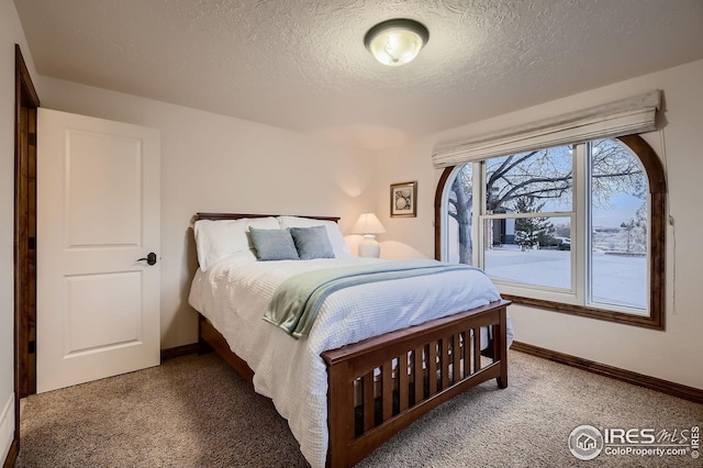 carpeted bedroom featuring a textured ceiling and baseboards