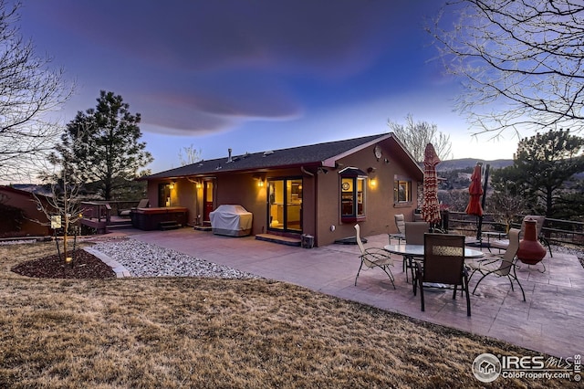 rear view of house featuring a patio area, a hot tub, stucco siding, and fence