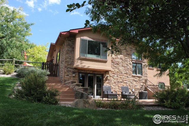 rear view of house with stairway, french doors, stone siding, and stucco siding