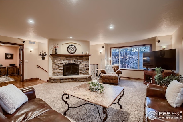 living room with a stone fireplace, visible vents, wood finished floors, baseboards, and recessed lighting