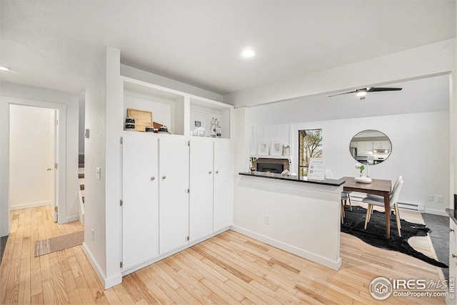 kitchen with recessed lighting, dark countertops, a peninsula, and light wood-style floors