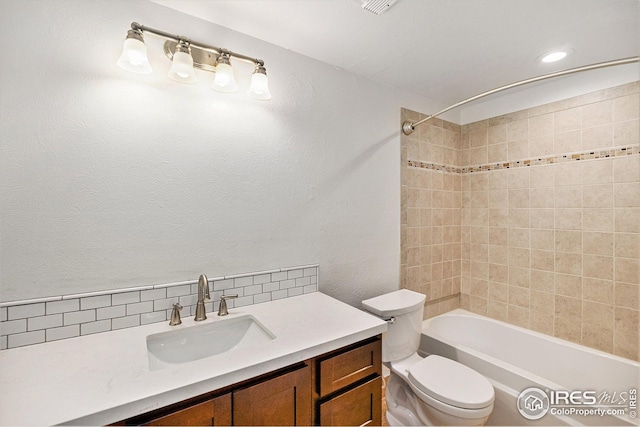 bathroom with vanity, decorative backsplash, toilet, and shower / washtub combination