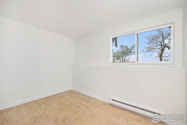 spare room with a baseboard heating unit, a healthy amount of sunlight, and light wood-type flooring