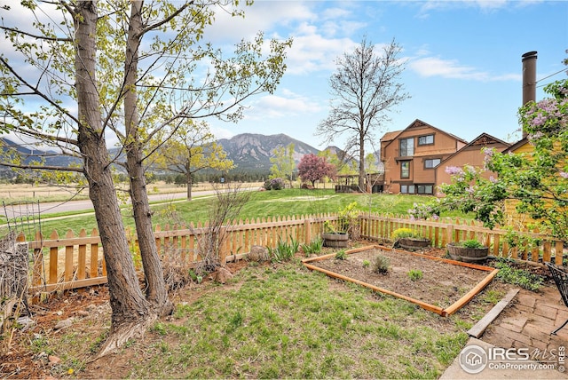 view of yard with fence, a mountain view, and a garden