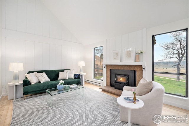 living room with baseboard heating, a warm lit fireplace, light wood-style flooring, and high vaulted ceiling