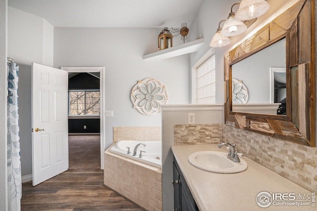 bathroom featuring a garden tub, wood finished floors, tasteful backsplash, and vanity