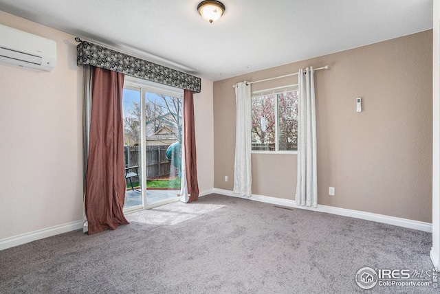 carpeted empty room featuring baseboards, visible vents, and a wall mounted air conditioner