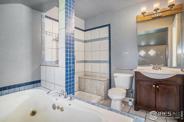 bathroom with vanity, tile patterned floors, a whirlpool tub, toilet, and a textured wall