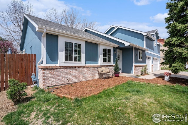 tri-level home with brick siding, a front lawn, fence, and driveway