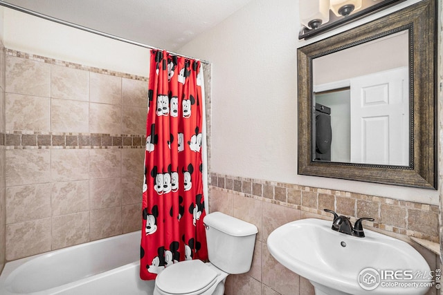 bathroom with a sink, tile walls, toilet, and shower / tub combo with curtain