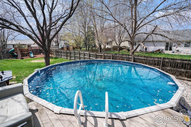 view of swimming pool with a lawn, a fenced in pool, a fenced backyard, and a playground