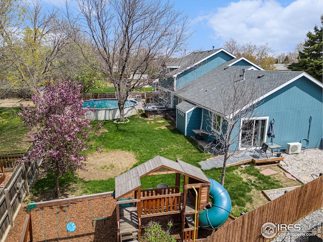 back of house with a fenced in pool, a fenced backyard, a playground, a yard, and a shingled roof