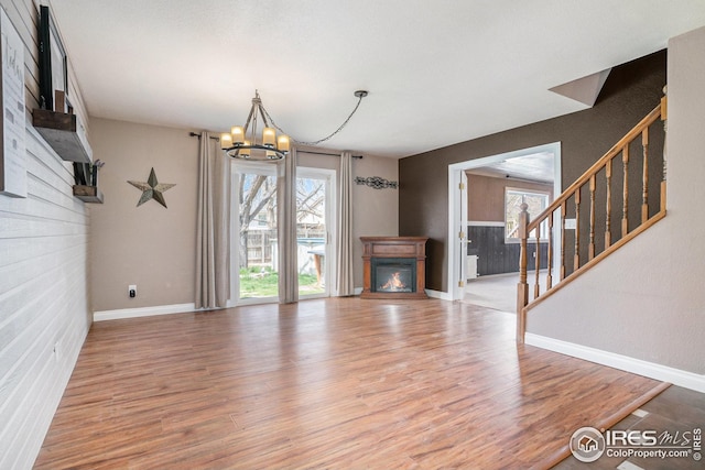 unfurnished living room with a glass covered fireplace, baseboards, and wood finished floors