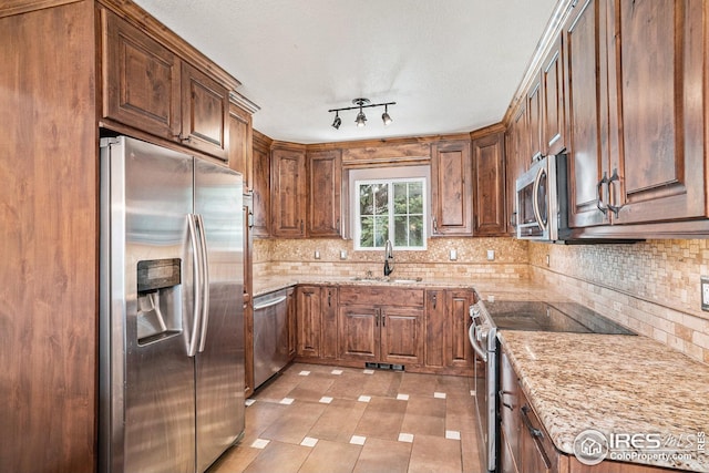 kitchen with backsplash, visible vents, appliances with stainless steel finishes, a sink, and light stone counters