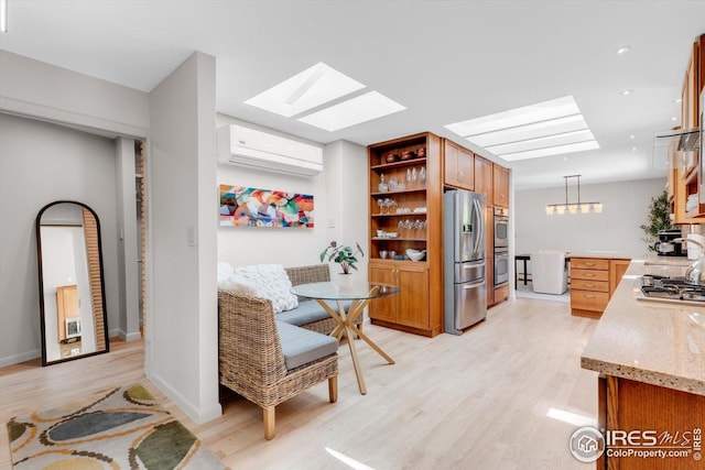 interior space featuring a skylight, baseboards, light wood-type flooring, and a wall mounted air conditioner