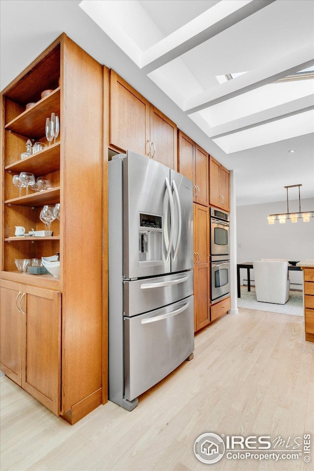 kitchen with stainless steel appliances, decorative light fixtures, brown cabinetry, and light wood-type flooring