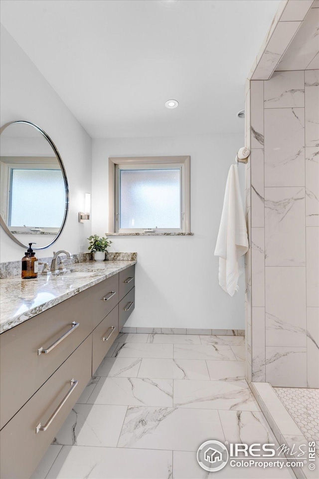 bathroom featuring marble finish floor, baseboards, a shower, and vanity