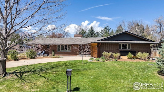 ranch-style home with a garage, a front lawn, a chimney, brick siding, and driveway