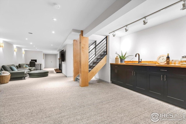 carpeted living room featuring wet bar, a sink, baseboards, stairway, and recessed lighting