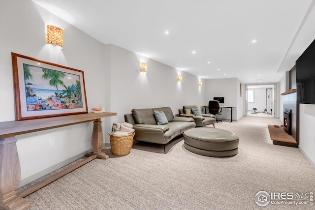 carpeted living area with recessed lighting, baseboards, and a warm lit fireplace