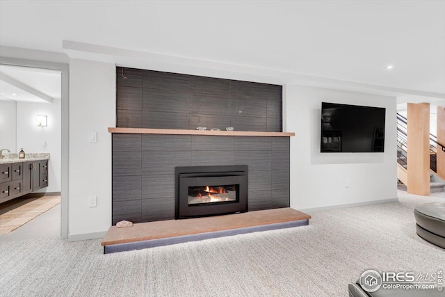 living area with carpet flooring, baseboards, and a fireplace