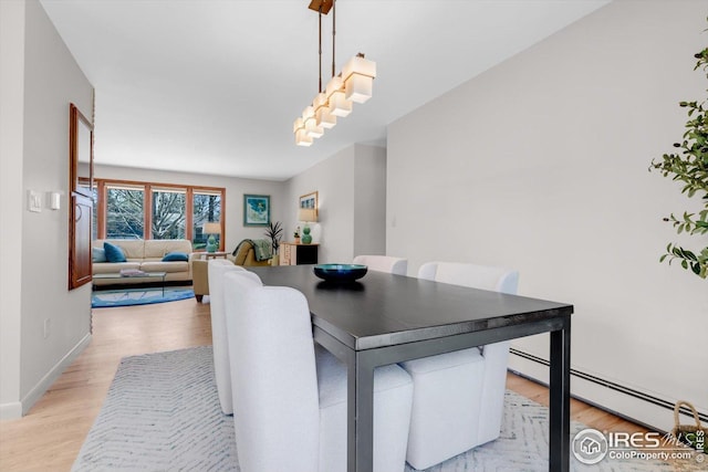 dining room with baseboards, a baseboard heating unit, and light wood-type flooring