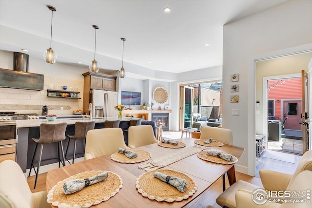 dining area with recessed lighting, a glass covered fireplace, and light wood-style floors