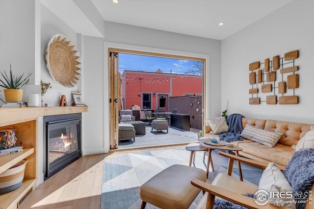 living room featuring a glass covered fireplace, recessed lighting, and wood finished floors