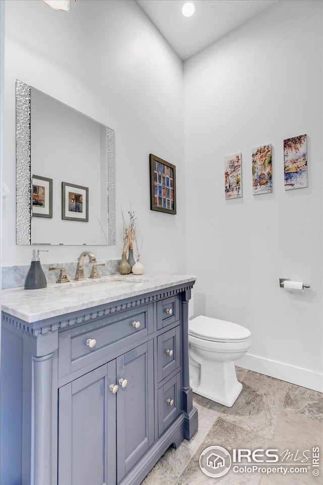 bathroom with baseboards, vanity, and toilet