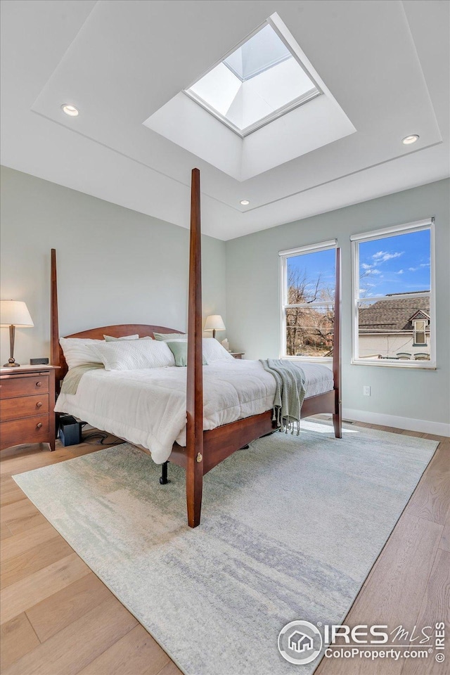 bedroom featuring baseboards, recessed lighting, a skylight, and wood finished floors