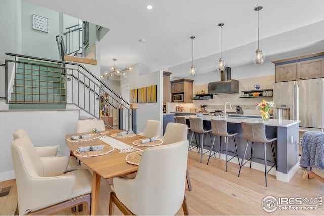 dining room with stairway, recessed lighting, an inviting chandelier, and light wood finished floors