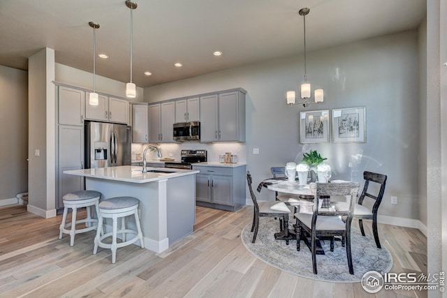 208 High Point Dr, Longmont, CO 80504 - kitchen with light wood-style floors, a sink, appliances with stainless steel finishes, a notable chandelier, and gray cabinetry