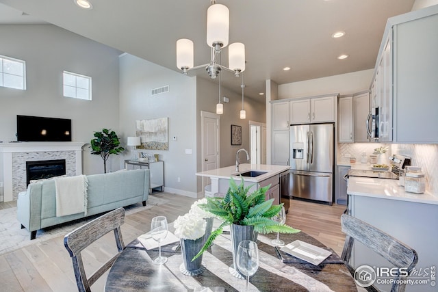 208 High Point Dr, Longmont, CO 80504 - dining area featuring visible vents, light wood finished floors, a fireplace, and high vaulted ceiling