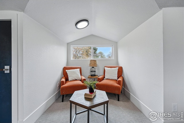 living area featuring carpet floors, a textured wall, and vaulted ceiling