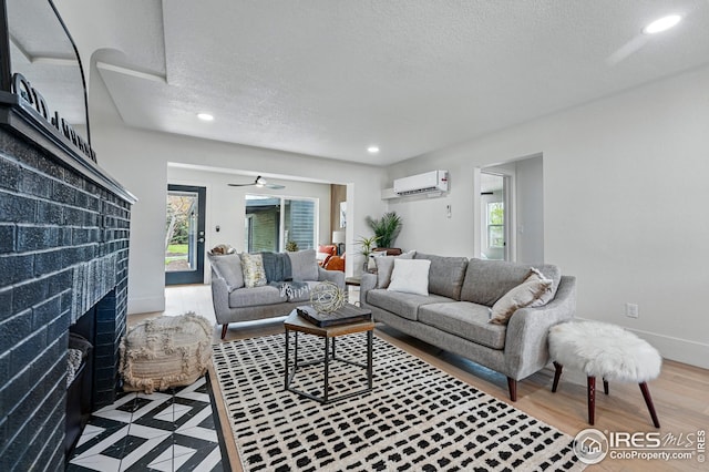 living room featuring recessed lighting, a textured ceiling, a wall mounted AC, and a wealth of natural light