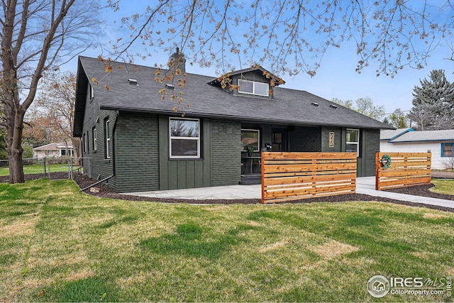 back of house with brick siding, a patio area, fence, and a yard